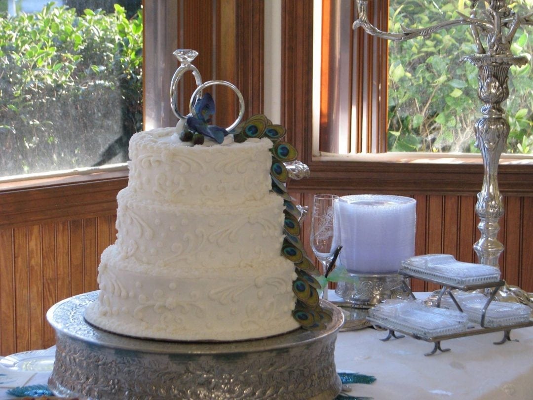 white wedding cake with peacock feathers